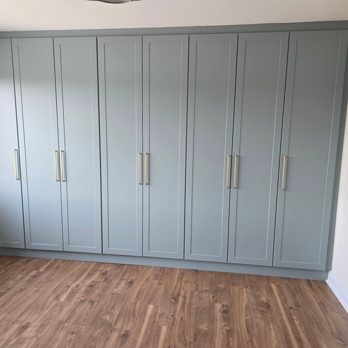 Sage-green shaker fitted wardrobes with brushed brass handles